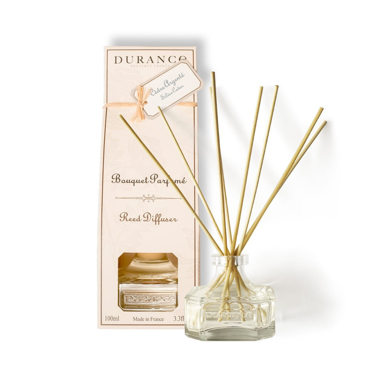 A Durance brand scented bouquet Silver Cedar Diffuser 100 ml with several gold-colored sticks, a clear glass vase, and a pink cardboard packaging box with the product name and weight information.